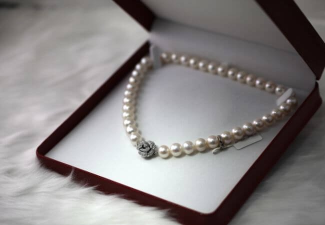 A pearl necklace in a box with a heart shaped clasp.