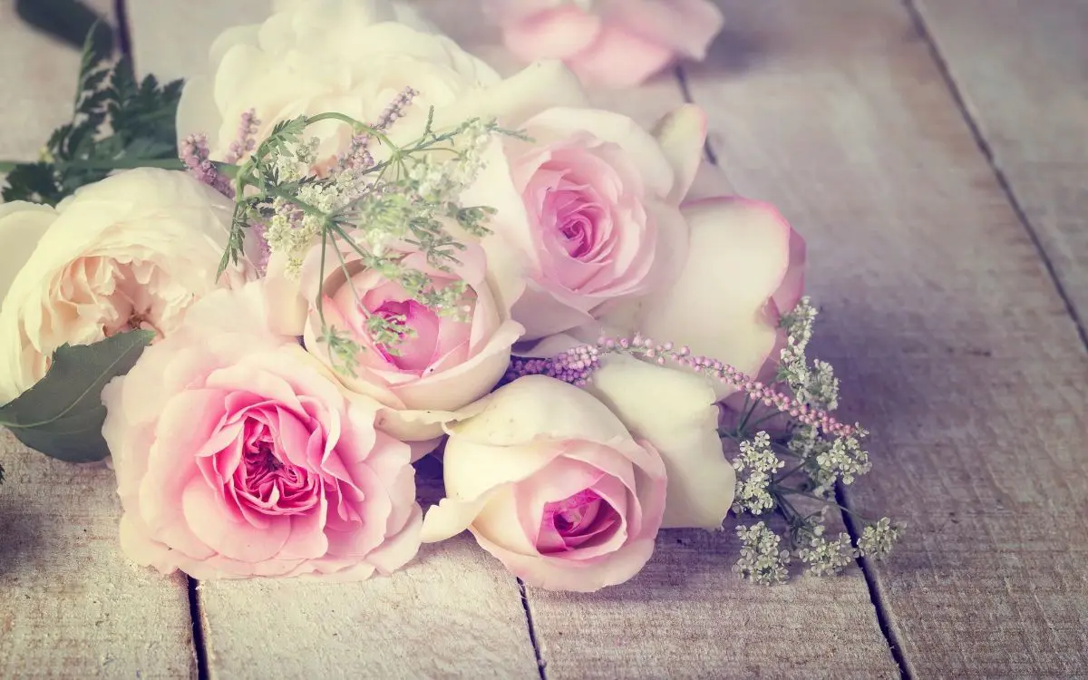 A bunch of pink roses on top of a wooden table.