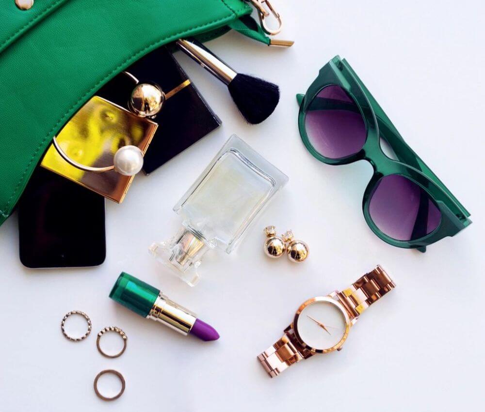 A purse, sunglasses and other accessories are laid out on the table.