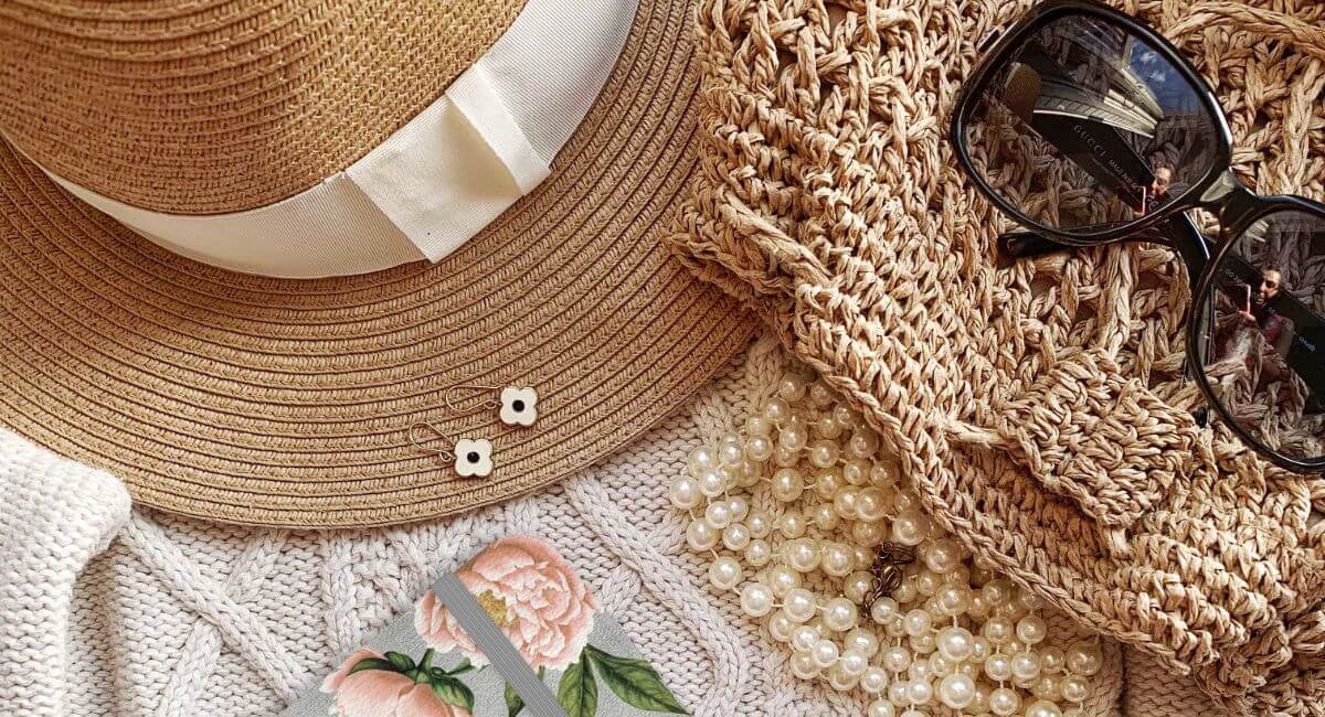 A straw hat, pearls and a bag on the ground.